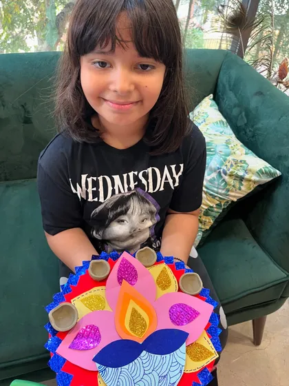 A student with her vibrant, multi-layered paper rangoli, a beautiful and safe decoration for Diwali.