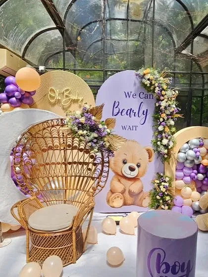 A detailed view of the 'We Can Bearly Wait' baby shower stage, highlighting the teddy bear, wicker chair, and custom backdrops.