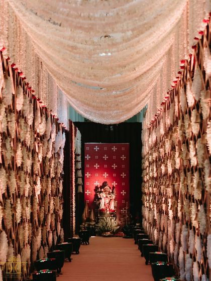 For this traditional Marathi wedding, the entrance to the ceremony was a dramatic passage lined with fragrant tuberoses. The design created a sensory experience for guests, leading them towards a sacred Ganesha idol, setting a tone of reverence and beauty.