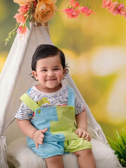 This happy little boy, one half of a twin pair, smiles brightly during his outdoor-themed tent photoshoot.