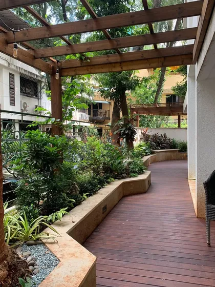 A beautiful, curved pathway made of wooden decking, flanked by raised planters, guides you through this lush ground-floor garden.