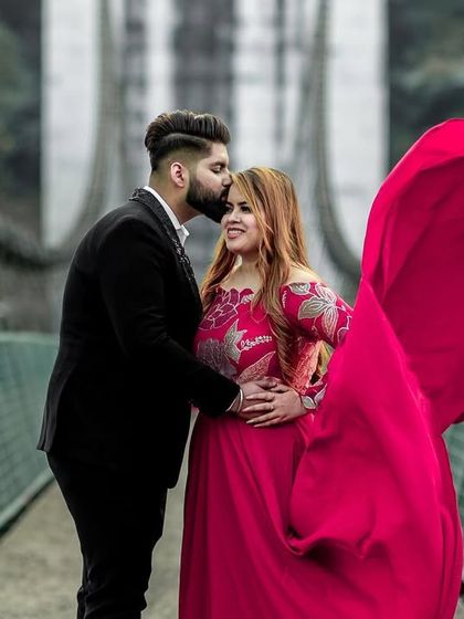 A beautiful moment on a bridge in Rishikesh, with the groom's tender kiss and the bride's flowing red dress creating a perfect pre-wedding portrait.