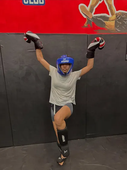 A female fighter in full gear, celebrating her power. Every punch, every kick, every drop of sweat makes you stronger and more fierce.