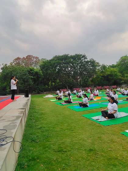 An instructor on stage guides a large group of participants in an outdoor yoga session. This image captures the essence of our community events, where we bring yoga to people from all walks of life.
