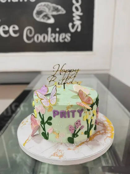 A garden-themed cake with butterflies and piped flowers, personalized for Prity.