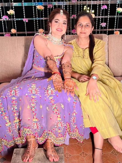 A bride sitting with her mother, both sharing a happy moment during the mehandi ceremony.