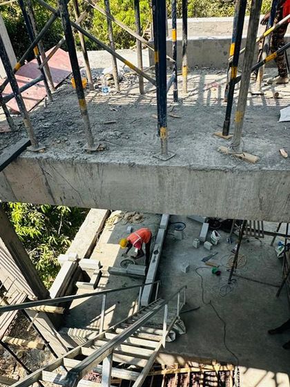 An overhead view of the villa's construction, showing workers on the cantilevered concrete slab. This perspective highlights the structural engineering required to achieve the 'floating' deck effect.