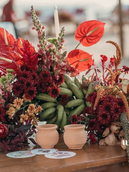 A centerpiece for the beach event, featuring tropical fruits like bananas and anthurium flowers.