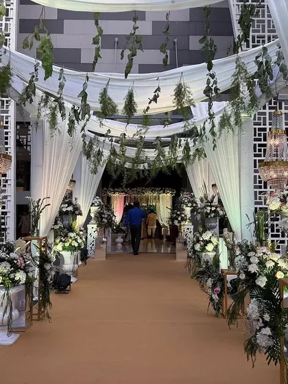 Draped in white fabric and hanging greenery, this entrance feels both grand and organic. The chandeliers add a touch of classic glamour to the rustic-chic design.