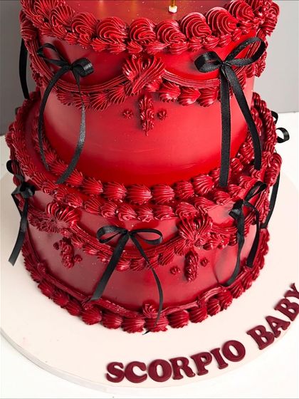 A detailed shot of the bottom tier of the red Scorpio cake, showing the intricate piping and the personalized message.