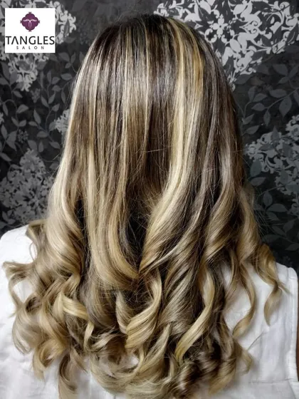 A view from the back, this image clearly displays the intricate placement of the golden blonde highlights. Notice how they are woven through the hair to create a full and vibrant look, styled here in classic curls.