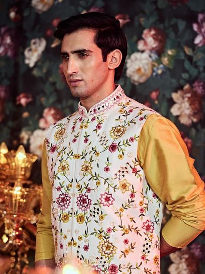 This Nehru jacket features a beautiful array of hand embellishments, including pearls and multi-color threadwork, for a festive baraati look.