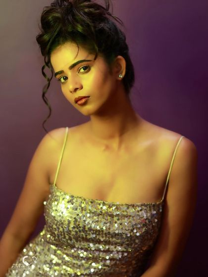 A beautiful portrait with dramatic lighting. The yellow light on her skin creates a warm glow against the cool purple background.