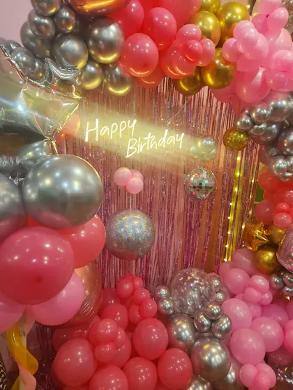 A close-up of the disco-themed decor, highlighting the mix of pink and gold balloons, shiny disco balls, and the bright neon sign.