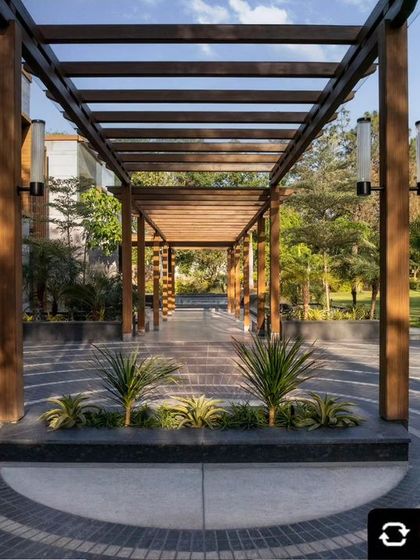 This image, featured in Elle Decor India, highlights the project's focus on eco-friendly building practices. The wooden pergola and stone facade are key elements of its sustainable design.