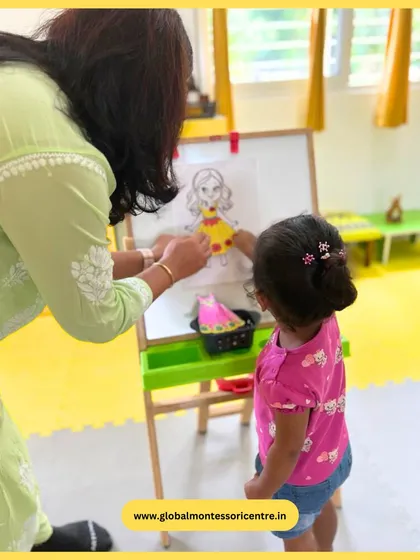 A child carefully places a piece of clothing on the figure, demonstrating the hand-eye coordination this activity is designed to build.