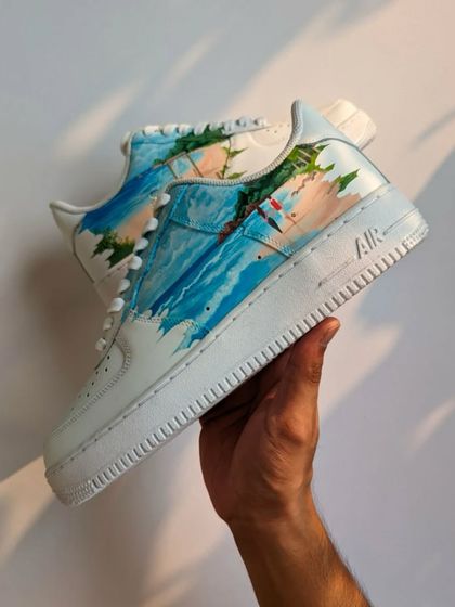 A beautiful pair of custom Air Force 1s for a couple who had a beach wedding. The design features a serene beachscape with their initials and wedding date in the sand.