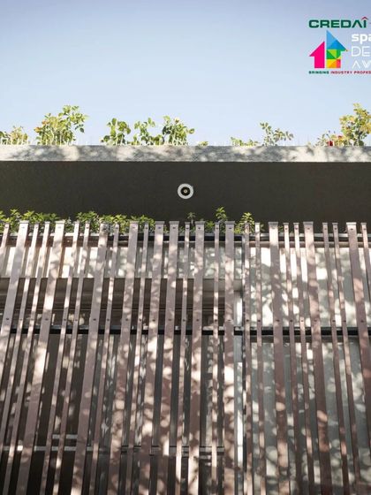 A detail of the upper facade screen, showing how shadows from the structure and nearby trees create complex patterns.