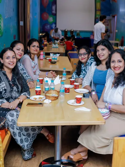 A group of mothers enjoying a conversation and snacks while their kids play.
