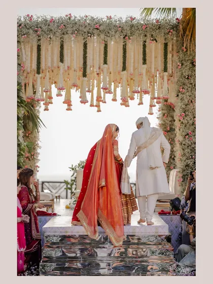 A beautiful moment as the couple takes their vows under a canopy of cascading florals. This design uses a mix of baby's breath and pink roses for a soft, romantic effect at the Taj Lands End.