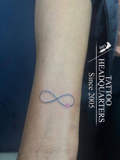 A simple infinity symbol with a small pink heart, a delicate and popular design for the wrist.