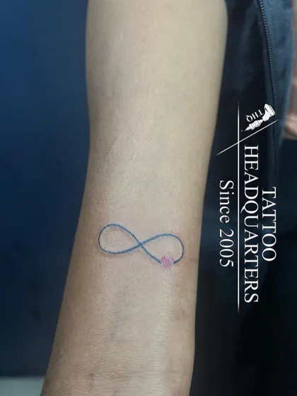 A simple infinity symbol with a small pink heart, a delicate and popular design for the wrist.