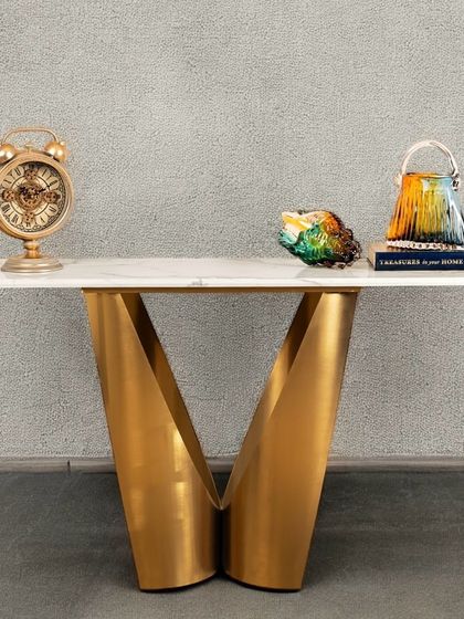 The Midnight Gold Console is the ultimate statement piece. Its dramatic V-shaped base is crafted from stainless steel with a gold finish, supporting a sleek artificial marble top. It’s a piece of sculptural art for your home.
