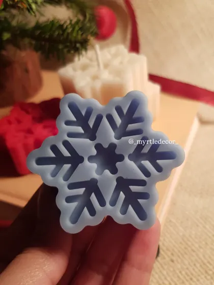 Holding one of our blue Snowflake Candles. You can see the crisp, detailed impression of the snowflake design, a result of our careful pouring process.