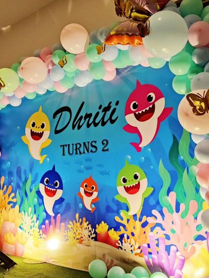 A close-up of a Baby Shark-themed backdrop, framed by a pastel-colored balloon garland.