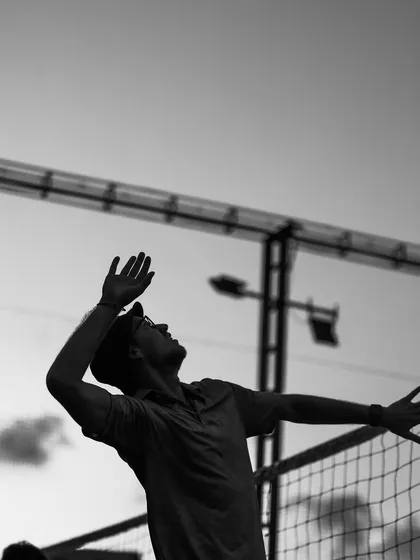 The follow-through of a serve, captured in a dramatic black and white silhouette.