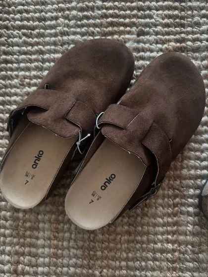 A close up of the dark brown suede-like clogs. They have a comfortable cork footbed and an adjustable strap.