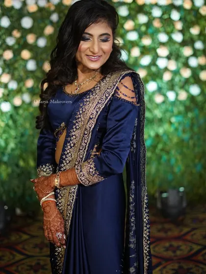 The complete reception look with a stunning navy blue saree. The smoky eye makeup and open hairstyle create a chic and modern vibe, perfect for a Bollywood-inspired look.