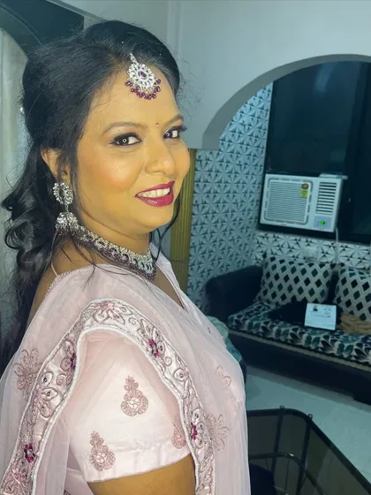 A happy client photo. The makeup features a shimmery eye, bold lip, and glowing skin, perfect for her festive attire.