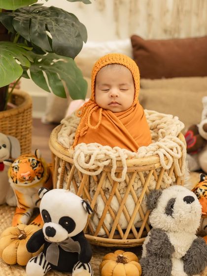 A sweet newborn boy all wrapped up in an orange swaddle and matching bonnet, looking so peaceful.