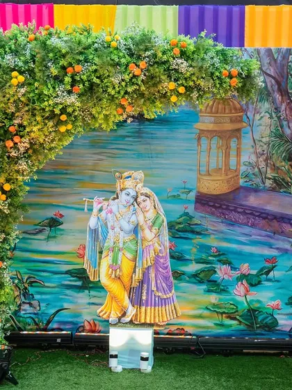 This beautiful photo booth features a serene Radha-Krishna painting as the backdrop. We framed it with a lush floral arch and colorful drapery, providing a divine setting for guests to capture memories at the Hiravati Banquet event.