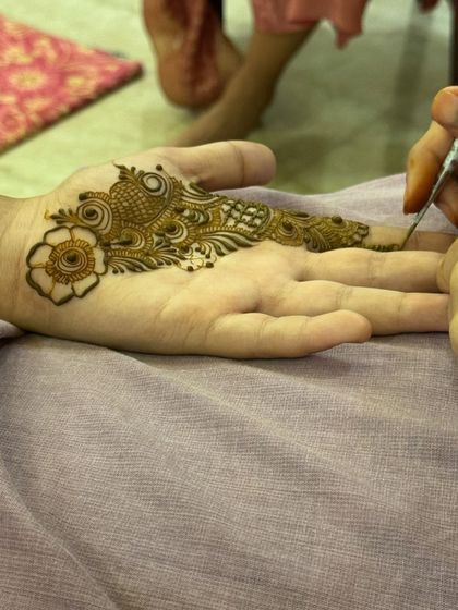 A work-in-progress shot of a modern design, showing the application of a bird motif on the palm.