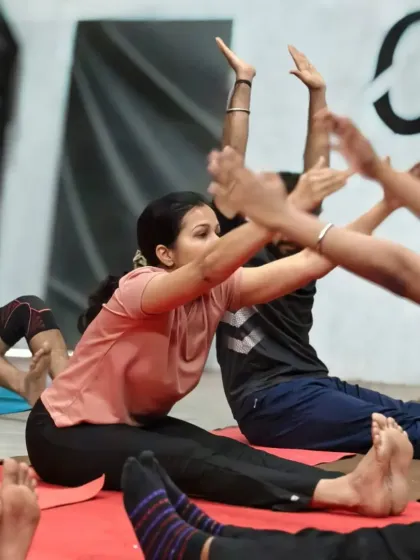 Teamwork makes the dream work. Members partner up for a seated forward bend (Paschimottanasana) variation, using each other for support to achieve a deeper hamstring and lower back stretch.