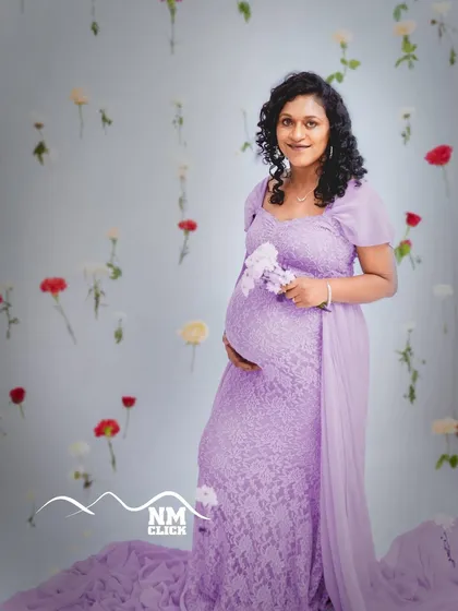 Our 'life-in-bloom' theme is a favorite among expecting mothers. Here, we used a backdrop of delicate hanging flowers to create a dreamy and ethereal portrait, perfectly complementing the soft lavender lace gown from our studio collection.