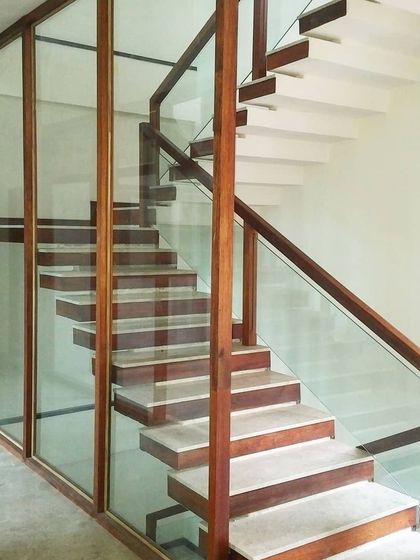 In another courtyard house, this hybrid staircase combines reinforced concrete steps with wood and glass railings, creating a floating effect that feels both sturdy and light.