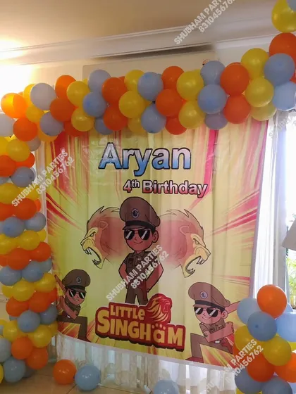 A Little Singham themed birthday party with a character banner and a balloon arch.