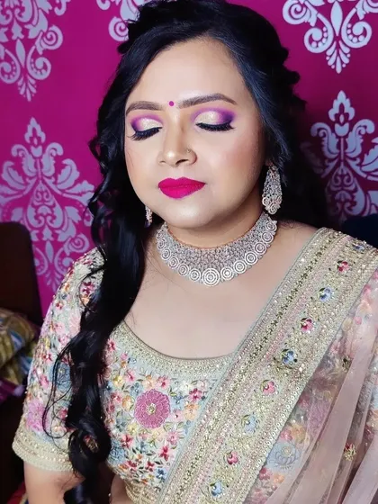 The soft, side-swept hairstyle complements the bold makeup and the intricate details of her pastel-colored lehenga.