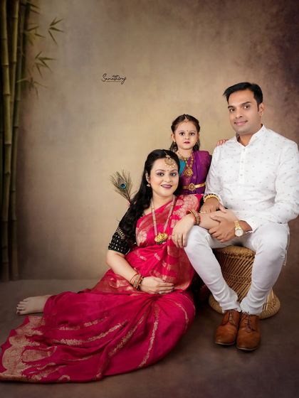 A beautiful family portrait from our traditional series. The mother, draped in a stunning pink saree, is joined by her husband and daughter, creating a timeless memory of their growing family.