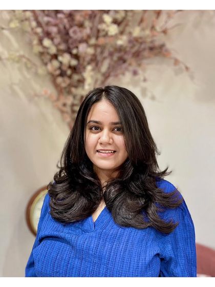 The client looking pleased with her new layer cut. The style is flattering and gives her hair a healthy, voluminous appearance.