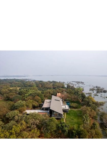 An expansive aerial view of the Lakeshore house, showing its position on the edge of Lake Osman Sagar. The design respects the vastness of the 50-acre site.
