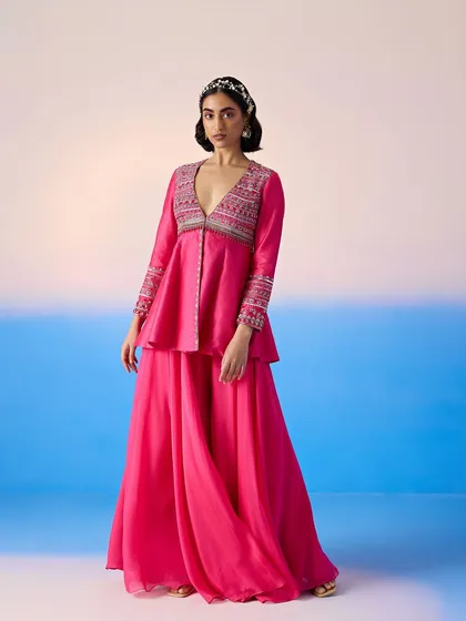 A full-length shot of the pink peplum sharara set, a modern and stylish ensemble for any celebration.
