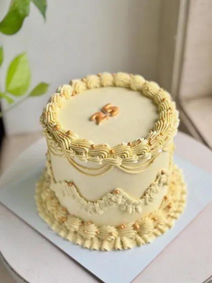 Golden hour, but make it cake. This vintage design in a warm yellow hue features intricate piping, scalloped edges, and tiny gold pearls for a touch of shimmer.