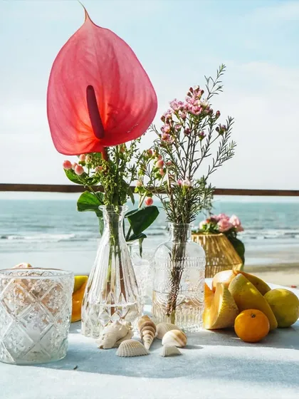 A simple yet stunning centerpiece of anthuriums and other delicate flowers against the backdrop of the sea.