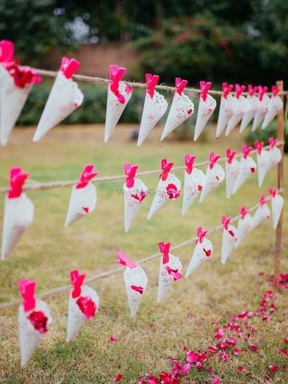 A creative way to distribute flower petals for the ceremony, with paper cones hanging on a rustic frame.