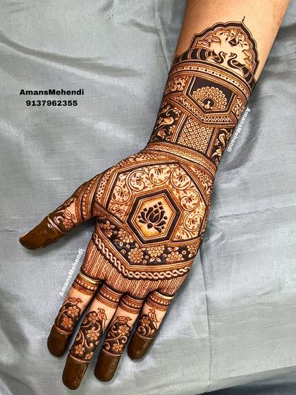 A full-hand design with a central lotus motif. The pattern extends up the arm with geometric shapes and peacock figures, creating a very full and intricate bridal look.