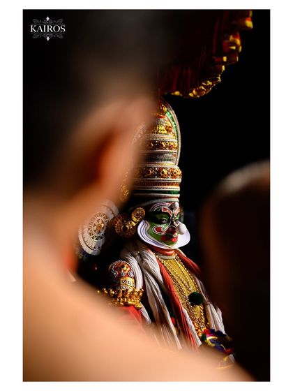A creatively framed shot of a Kathakali dancer, using foreground elements to create a sense of looking in on a private, powerful moment.